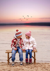 happy cute children sitting together at the beach in sunset light