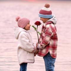 cute boy and girl in love on the beach with a red rose