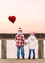 girl and boy holding heart shaped balloons