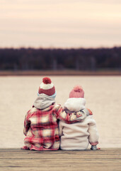 small boy is hugging his girlfriend on the wooden pier on Valentines day