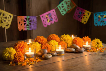 Calaverita Literaria Decorative Altar Elements. Still-life composition of symbolic Calaverita literaria altar elements marigold flowers, candles, decorative stones, papel picado strips, warm soft glow