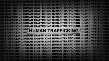 A strip of newspaper with the words Human Trafficking typed on it. Black and white. Close up.