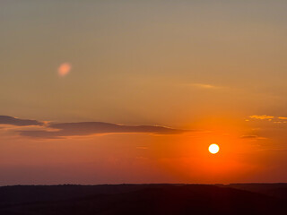 Golden sun setting over dark rolling hills landscape
