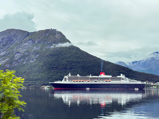 Cruise ship sailing norwegian fjord under cloudy sky