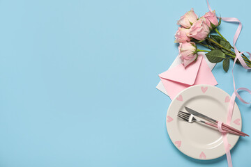 Beautiful table setting for Valentine's Day with envelope and rose flowers on blue background