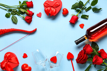 Frame made of cupid's bow, arrow, bottle of wine and rose flowers on blue background. Valentine's...