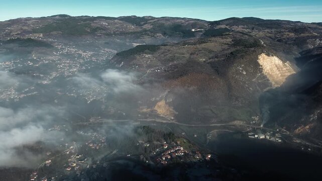 Aerial view of dense clouds covering valleys with snowy mountain ridges rising above the fog, creating a dramatic winter landscape near Sarajevo with clear sky and natural contrast