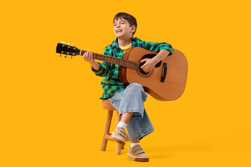 Naklejka premium Cute boy playing guitar on yellow background