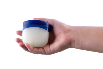 Hand holding a small jar of petroleum jelly, isolated on a black background