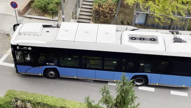 Autob&uacute;s circular azul de transporte p&uacute;blico arrancando en salida de parada y marquesina iniciando ruta