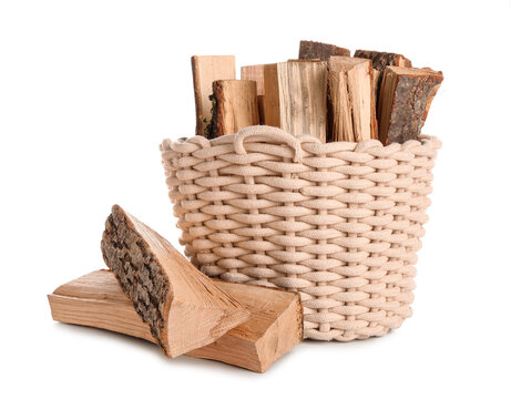Wicker basket with firewood logs on white background