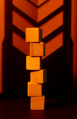 Stacked Wooden Blocks Tower Cast in Warm Orange Lighting With Geometric Backdrop