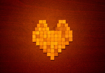A heart shape built from small wooden cubes rests on a warm, textured brown background.