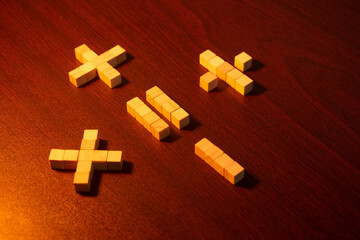 Set Of Wooden Blocks Forming Math Symbols on dark surface.