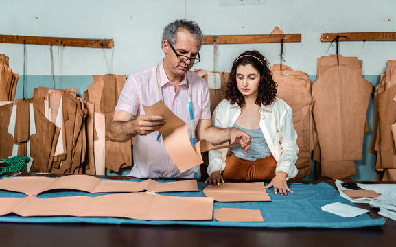 Professional Tailor and Young Apprentice Working with Paper Patterns in a Garment Workshop - Powered by Adobe
