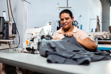 A skilled female seamstress working on an industrial sewing machine in a textile factory, manufacturing garments with precision.
