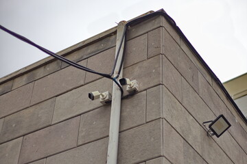 Obraz premium Two CCTV cameras on the building's facade. Close-up of the cameras against a brick wall. Smart city concept. City safety and security.