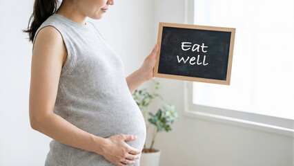 Pregnant woman holding a blackboard with eat well message, healthy lifestyle nutrition guidance, expectant mother prenatal care and wellness concept in bright room