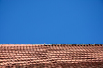 A wide horizontal shot of a traditional red clay tile roof against a vast and clear blue sky...
