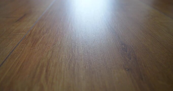 Close-up sliding footage of sunlit oak laminate flooring in a modern home