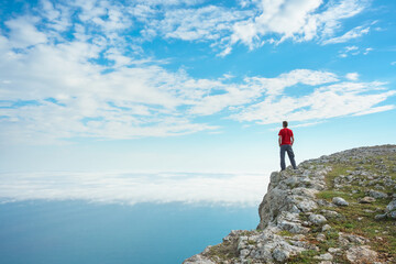 Man on sea cliff edge and blue sky at spring day.