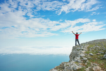 Man on sea cliff edge and blue sky at spring day.