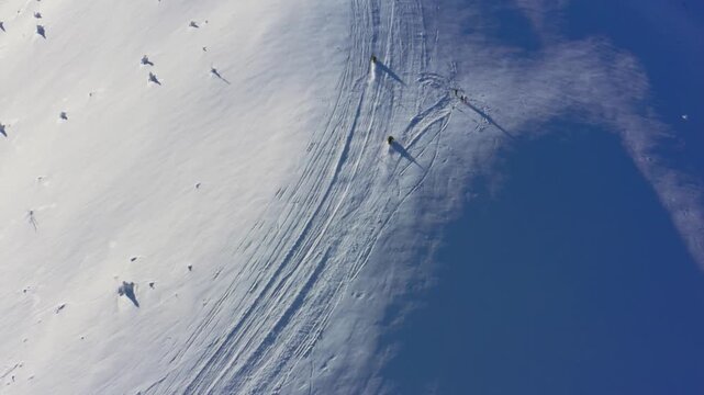 A fast man on a snowmobile rides a deserted slope of a snowy mountain at a bright sunset