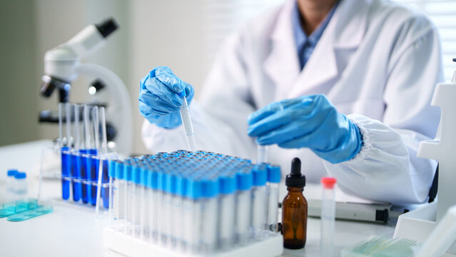 Adult scientist hands pipetting blue liquid test tubes conducting lab experiment medical research drug discovery in science laboratory
