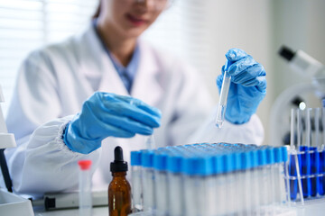 Asian adult woman scientist conducts laboratory experiment research using test tubes in professional medical science facility for biotechnology analysis discovery