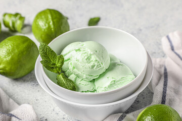 Bowl with lime ice cream and mint leaves on light grunge background © Pixel-Shot