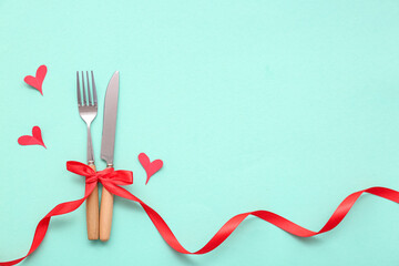 Composition with cutlery, ribbon and paper hearts on mint background. Valentine's Day celebration