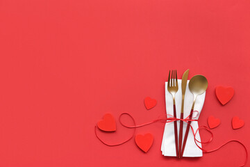 Composition with cutlery, napkin and decorative hearts on red background. Valentine's Day...