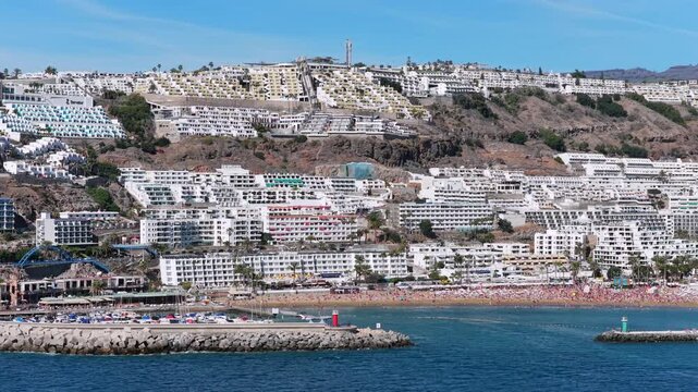 The Terraced Paradise: 4K Aerial of People Relaxing at Luxury Cliffside Resorts Overlooking Puerto Rico Marina and the Atlantic Coastline, Gran Canaria, Spain