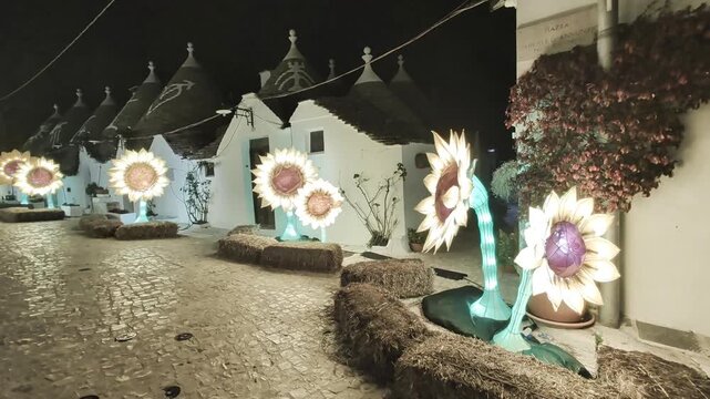 Trulli di Alberobello di notte con installazioni luminose a forma di girasole per Natale