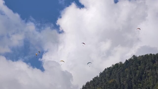 Low angle view of paragliders flying against blue sky and white clouds in Interlaken, Switzerland