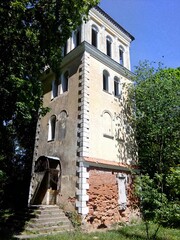 vintage building facade, a weathered, multi-story building with climbing plants has arched windows and a worn yellow facade, with brick peeking through