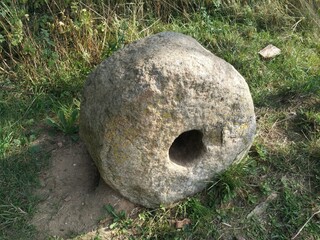 natures focal point, a smooth, round stone with a hole in the center sits on grass, surrounded by...
