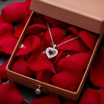 A red heart shaped gift box with a gold ribbon holds a jewelry treasure of pearls and gems, creating a beautiful holiday celebration present isolated for Christmas