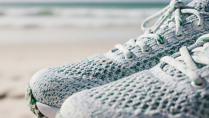 Macro shot of sneakers made from recycled ocean plastic on a white sand beach background