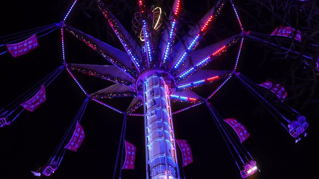 Colorful illuminated swing carousel amusement ride at a Christmas market in Paris at night