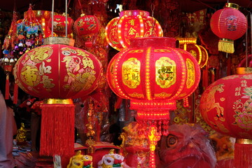 Vibrant red Chinese lanterns with gold calligraphy and tassels illuminate a festive market stall