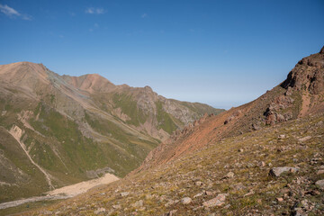 Winding gravel road in the high mountains of Tien Shan with a view of the massive Tuyuksu glacier. Remote alpine landscape in Central Asia