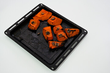 Baked pumpkin dessert with walnuts in oven tray on white background, organic natural sweet with botanical ingredients for wellness and harmony, eco friendly healthy food concept.