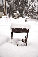 Old metal barbecue grill covered with thick fresh snow in a winter garden. Abandoned outdoor BBQ in snowy backyard, symbol of cold season, quiet atmosphere and frozen countryside life
