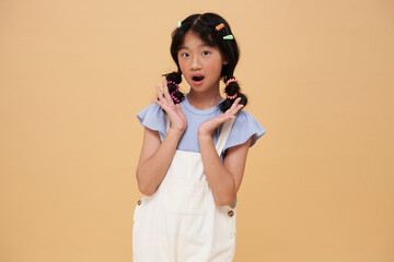 Surprised Asian girl with playful have fun isolated on pastel background child studio portrait. childlike emotion and creative expression