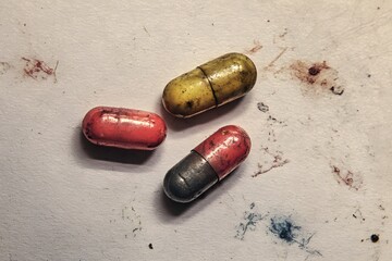 Colorful capsules in red, yellow, and black lying on a textured surface, showcasing pharmaceutical products and their vibrant appearance in a clinical setting