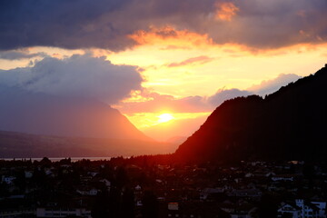 Dramatic sunset over the mountains of Interlaken, Switzerland with golden light rays through clouds