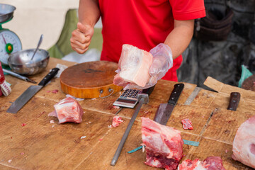 Butcher holding fresh raw meat at traditional Asian market stall