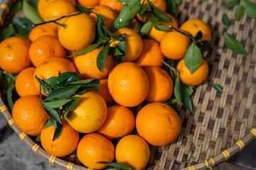 Fresh mandarins with green leaves in woven basket at Asian market