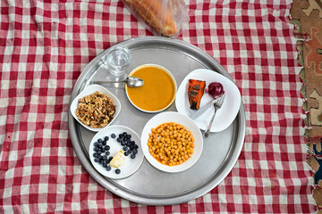 Traditional Turkish rural floor table with organic lentil soup, chickpeas and pumpkin dessert on a red checkered cloth, authentic Black Sea region food for wellness and healthy lifestyle.